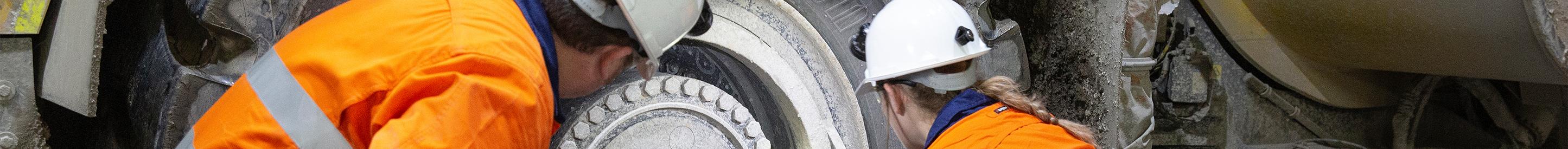 Workers inspecting vehicle wheel at mine site