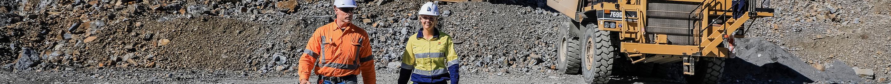 Workers at mine site walking toward the camera with haul truck in background