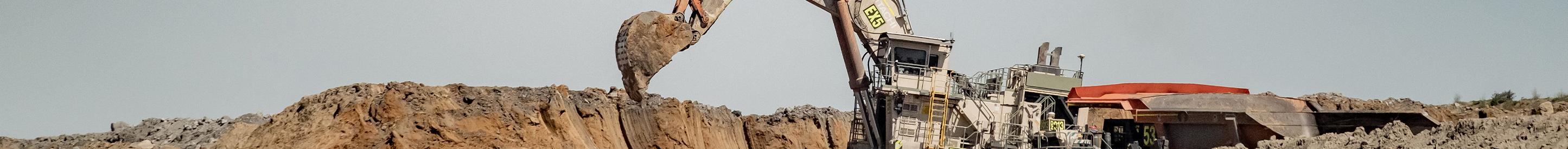Digger loading earth into haul truck at mine
